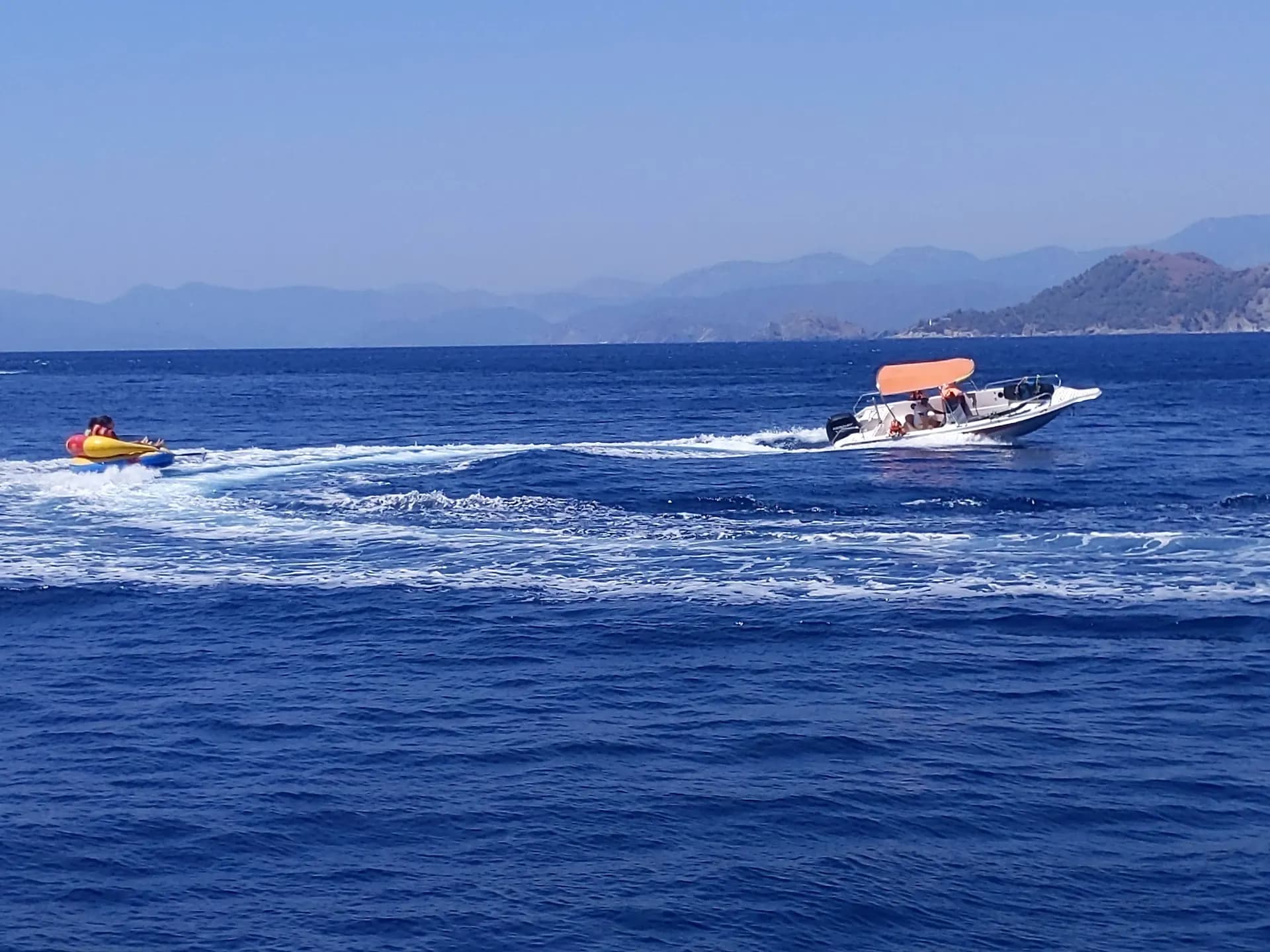 Crew with paddleboards and water toys off the boat
